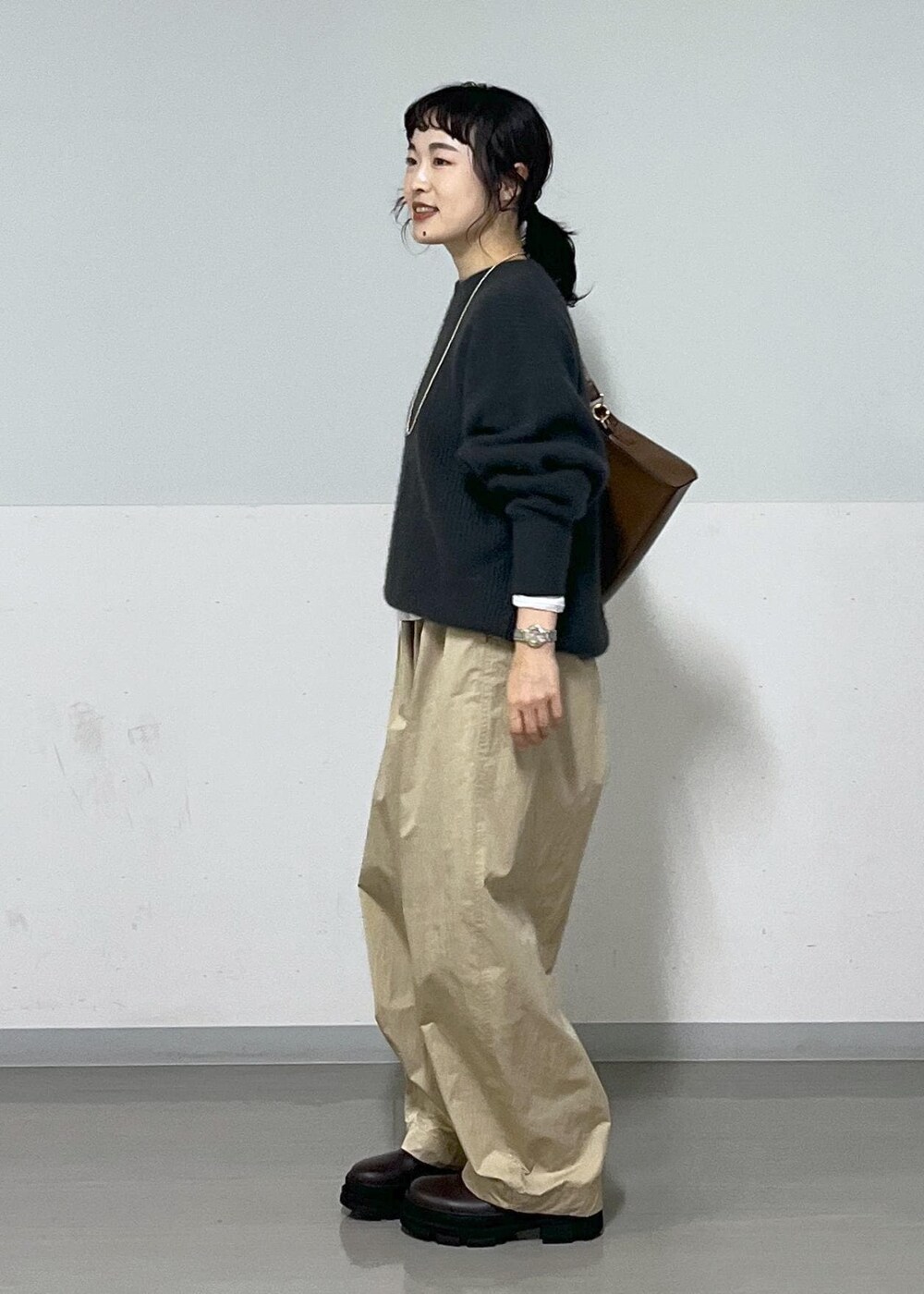 ホワイト系のTシャツ/カットソー、ブラウン系のショルダーバッグ、グレー系のニット/セーターを着用したレディースの秋コーディネートの2枚目の写真