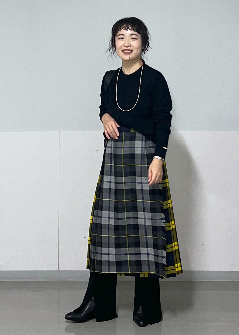 ブラック系のブーツ、グレー系のスカート、ブラック系のカーディガン/ボレロを着用したレディースの秋コーディネートの2枚目の写真