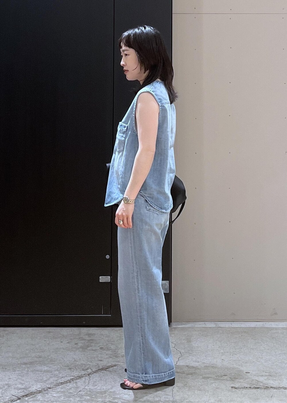 ホワイト系のキャミソール、ブラック系のサンダル、ブルー系のベストを着用したレディースの春コーディネートの2枚目の写真