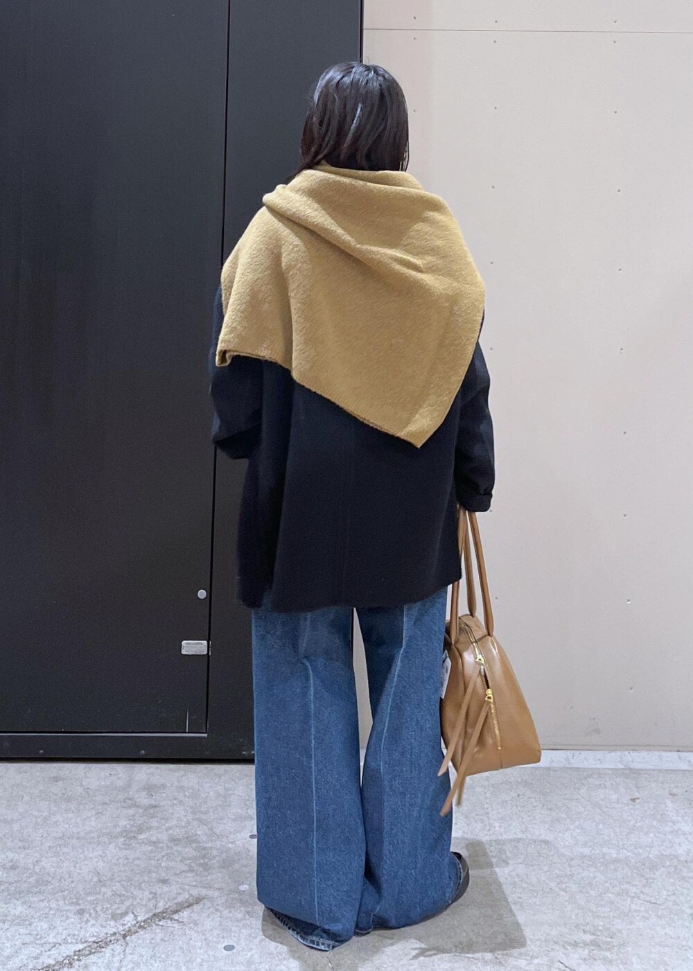 イエロー系のニット/セーター、ブルー系のデニムパンツ、ブラック系のその他アウターを着用したレディースの冬コーディネートの3枚目の写真