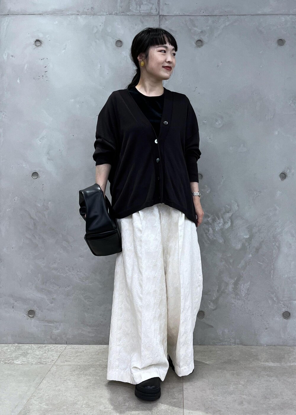 ブラック系のTシャツ/カットソー、ブラック系のハンドバッグ、ブラック系のブーツを着用したレディースの夏コーディネートの2枚目の写真