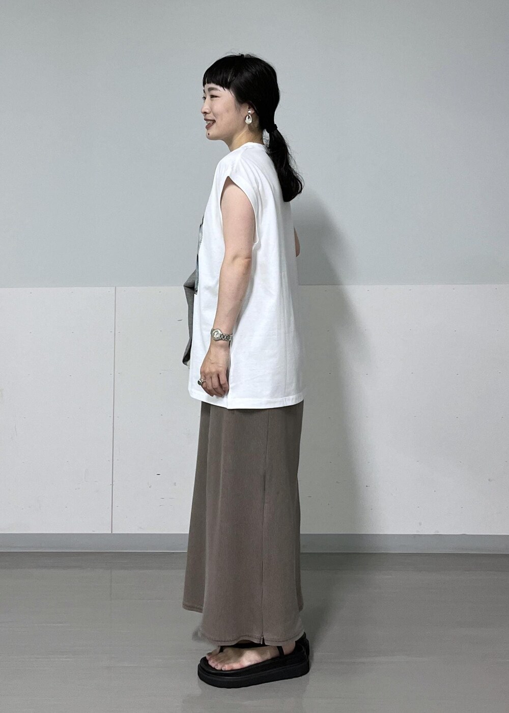 ブラック系のベスト、ホワイト系のTシャツ/カットソー、ブラック系のサンダルを着用したレディースの夏コーディネートの5枚目の写真