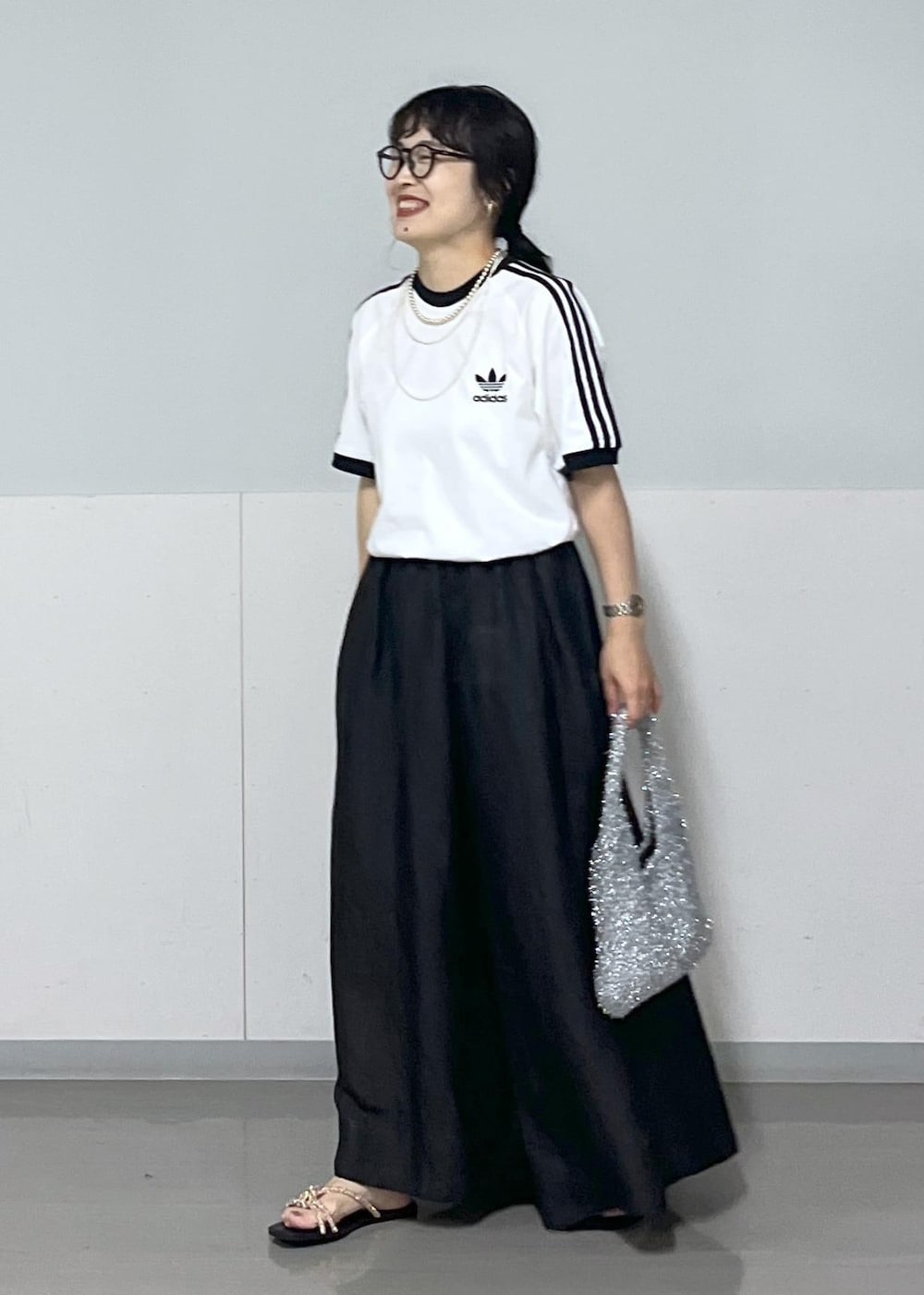 ブラック系のスカート、ゴールド系のサンダル、シルバー系のハンドバッグを着用したレディースの夏コーディネートの2枚目の写真