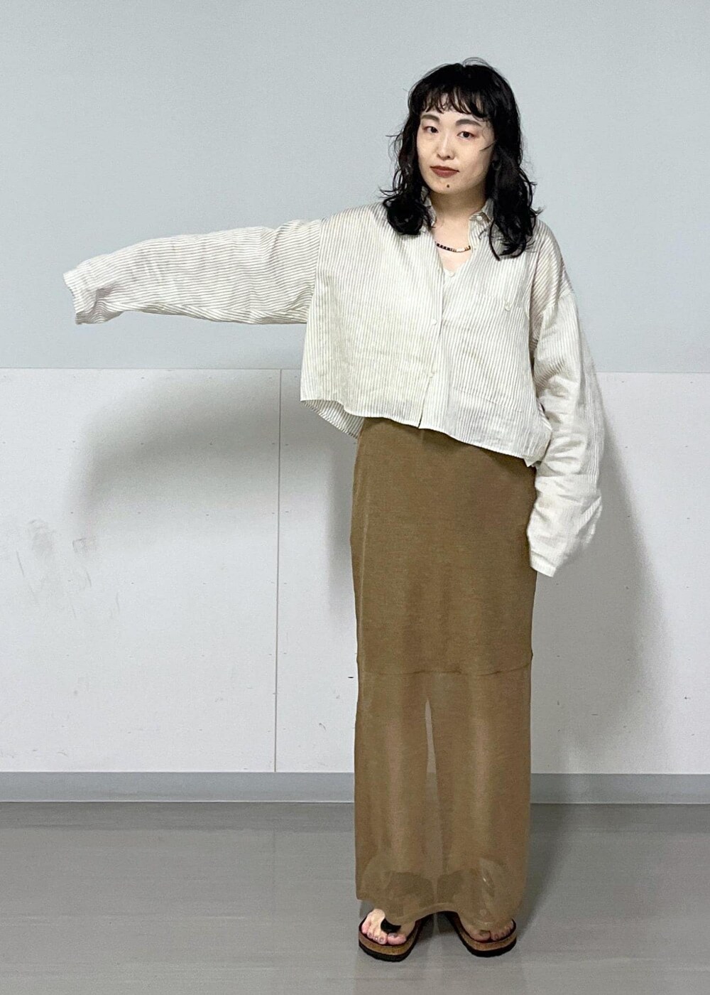 ブラック系のハンドバッグ、ホワイト系のシャツ/ブラウス、ゴールド系のスカートを着用したレディースの夏コーディネートの3枚目の写真