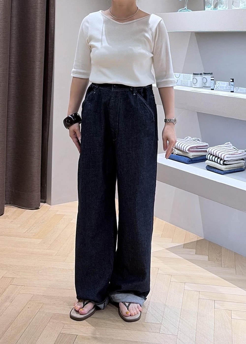 ブラック系のハンドバッグ、ベージュ系のサンダル、ブルー系のデニムパンツを着用したレディースの夏コーディネートの5枚目の写真