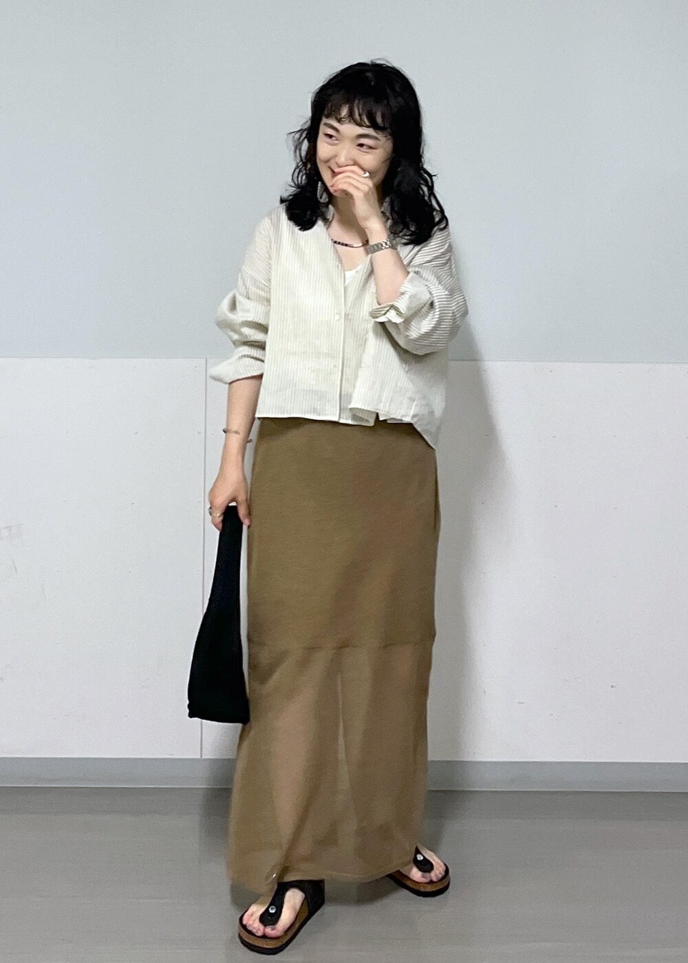 ブラック系のハンドバッグ、ホワイト系のシャツ/ブラウス、ゴールド系のスカートを着用したレディースの夏コーディネートの2枚目の写真