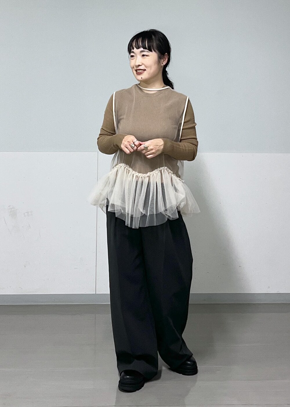 ブラック系のその他パンツ、ブラック系のブーツ、ホワイト系のベストを着用したレディースの秋コーディネートの3枚目の写真