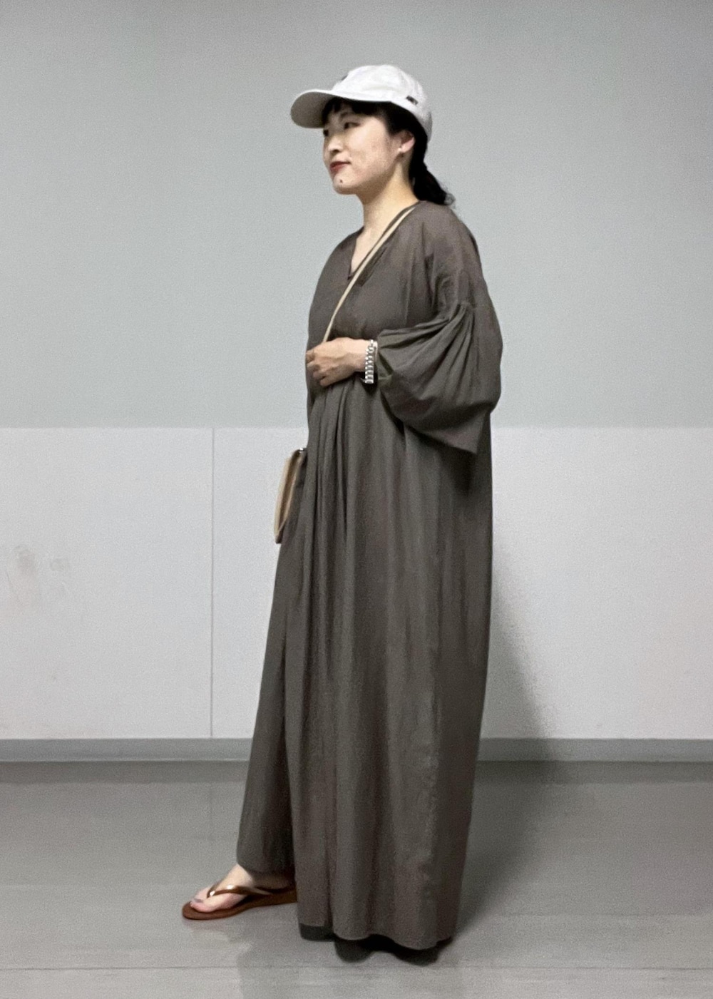 ブラウン系のサンダル、ベージュ系のショルダーバッグ、グレー系のワンピースを着用したレディースの夏コーディネートの2枚目の写真