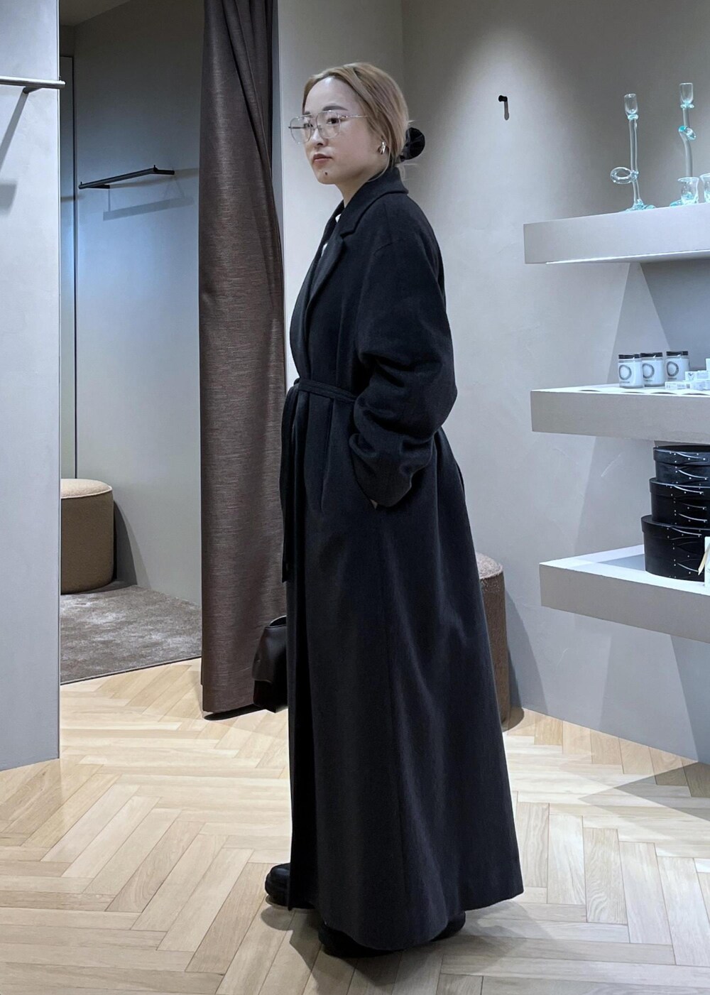 ブラック系のブーツ、ベージュ系のカーディガン/ボレロ、グレー系のトレンチコートを着用したレディースの冬コーディネートの3枚目の写真