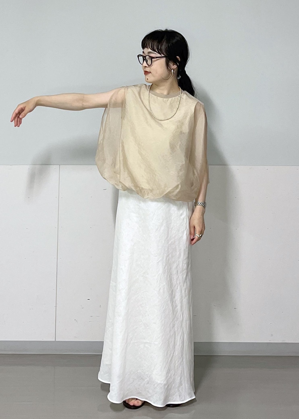 ブラック系のサンダル、ホワイト系のスカート、ベージュ系のTシャツ/カットソーを着用したレディースの春コーディネートの4枚目の写真