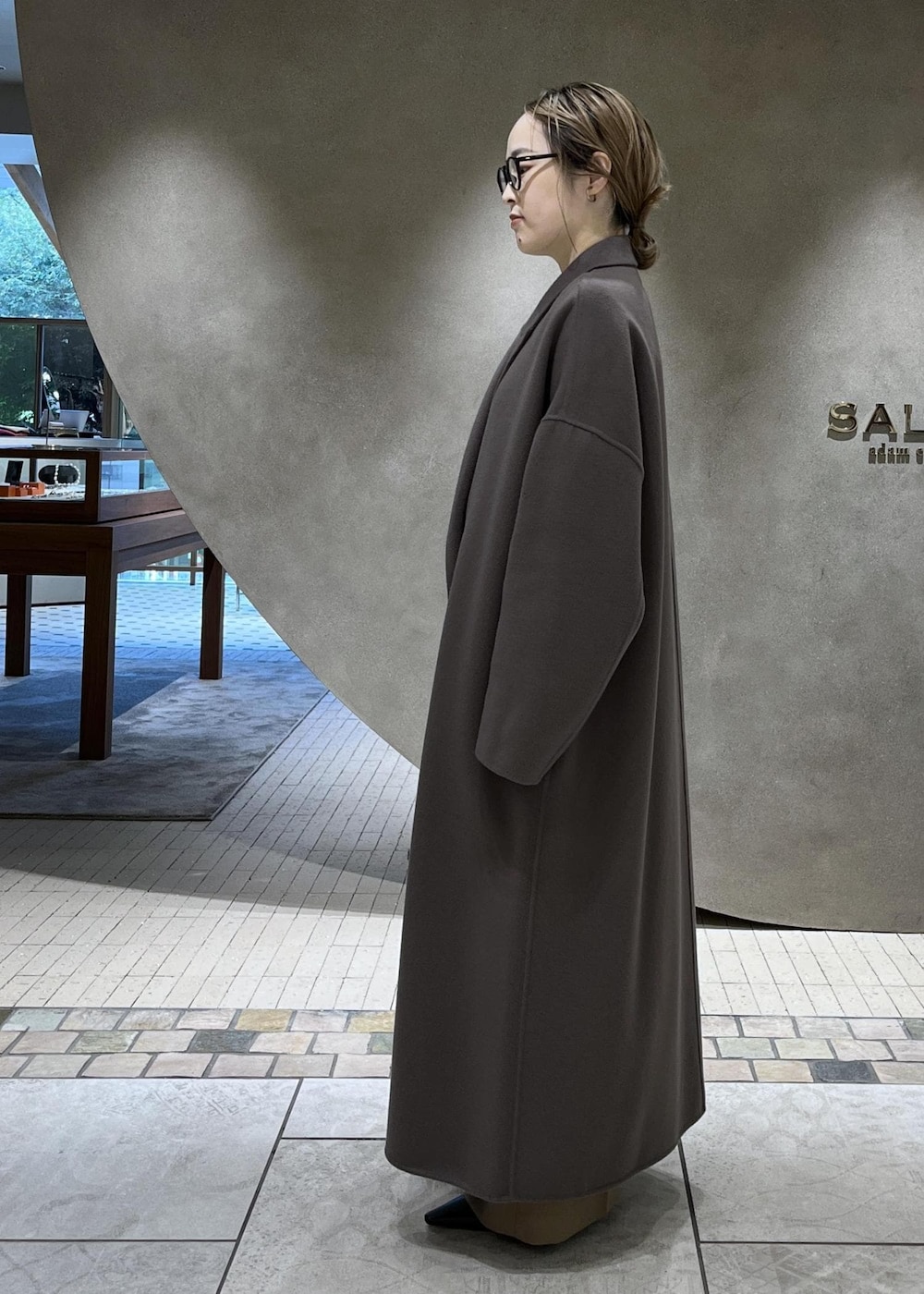 ベージュ系のスラックス、ベージュ系のチェスターコート、ホワイト系のニット/セーターを着用したレディースの秋コーディネートの5枚目の写真