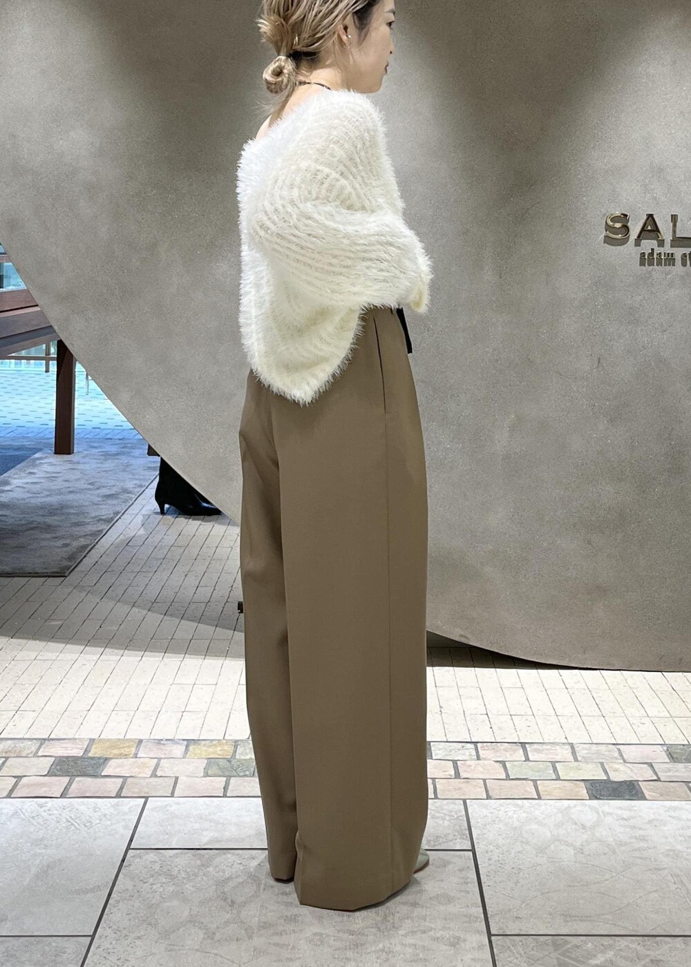 ベージュ系のスラックス、ベージュ系のチェスターコート、ホワイト系のニット/セーターを着用したレディースの秋コーディネートの10枚目の写真