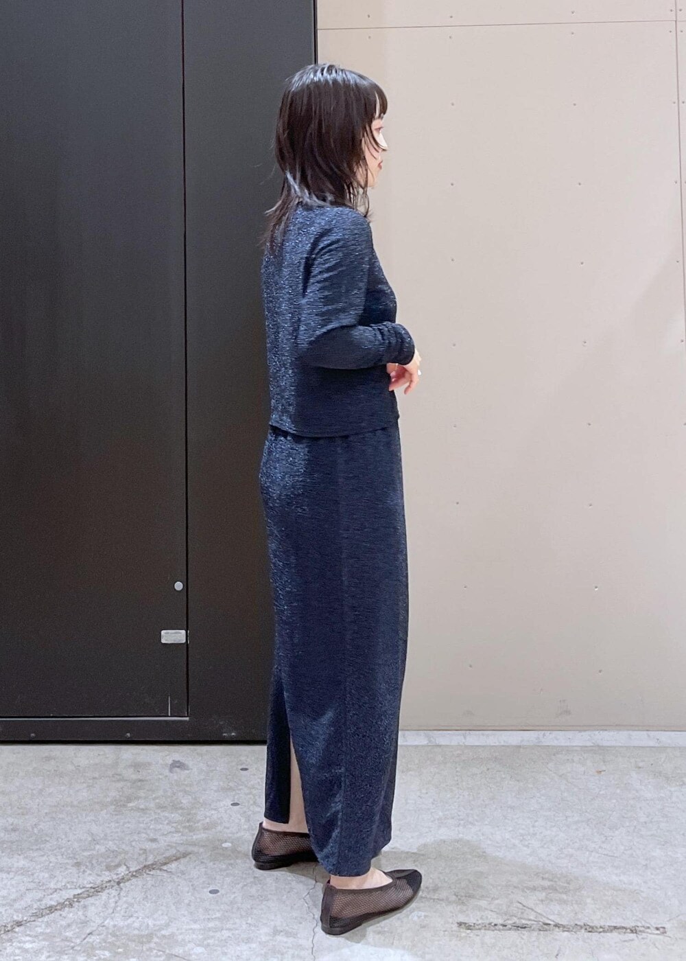 ブラック系のトートバッグ、ブラック系のパンプス、ブルー系のスカートを着用したレディースの冬コーディネートの5枚目の写真