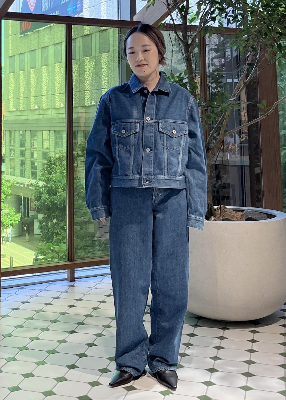 ベージュ系のショルダーバッグ、ブラック系のダウンジャケット/コート、ブルー系のデニムジャケットを着用したレディースの秋コーディネートの4枚目の写真