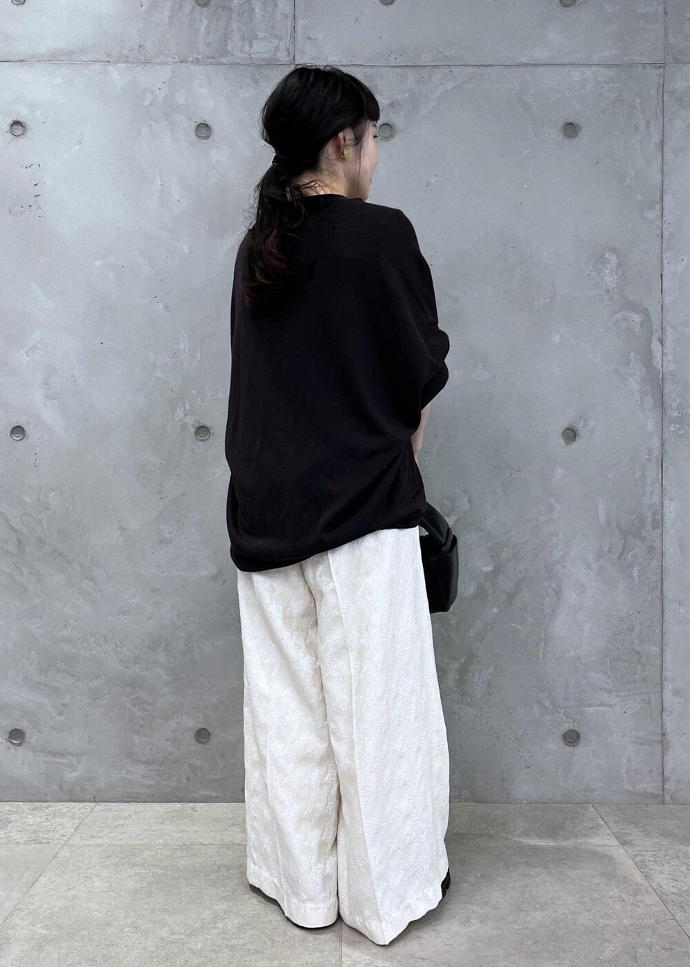 ブラック系のTシャツ/カットソー、ブラック系のハンドバッグ、ブラック系のブーツを着用したレディースの夏コーディネートの4枚目の写真