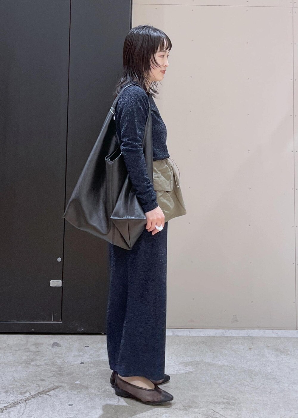 ブラック系のトートバッグ、ブラック系のパンプス、ブルー系のスカートを着用したレディースの冬コーディネートの2枚目の写真