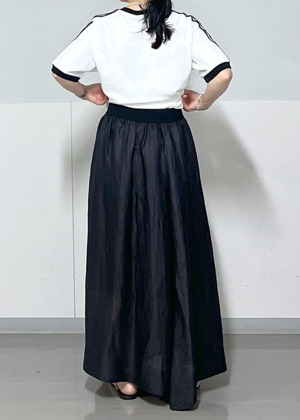 ブラック系のスカート、ゴールド系のサンダル、シルバー系のハンドバッグを着用したレディースの夏コーディネートの4枚目の写真