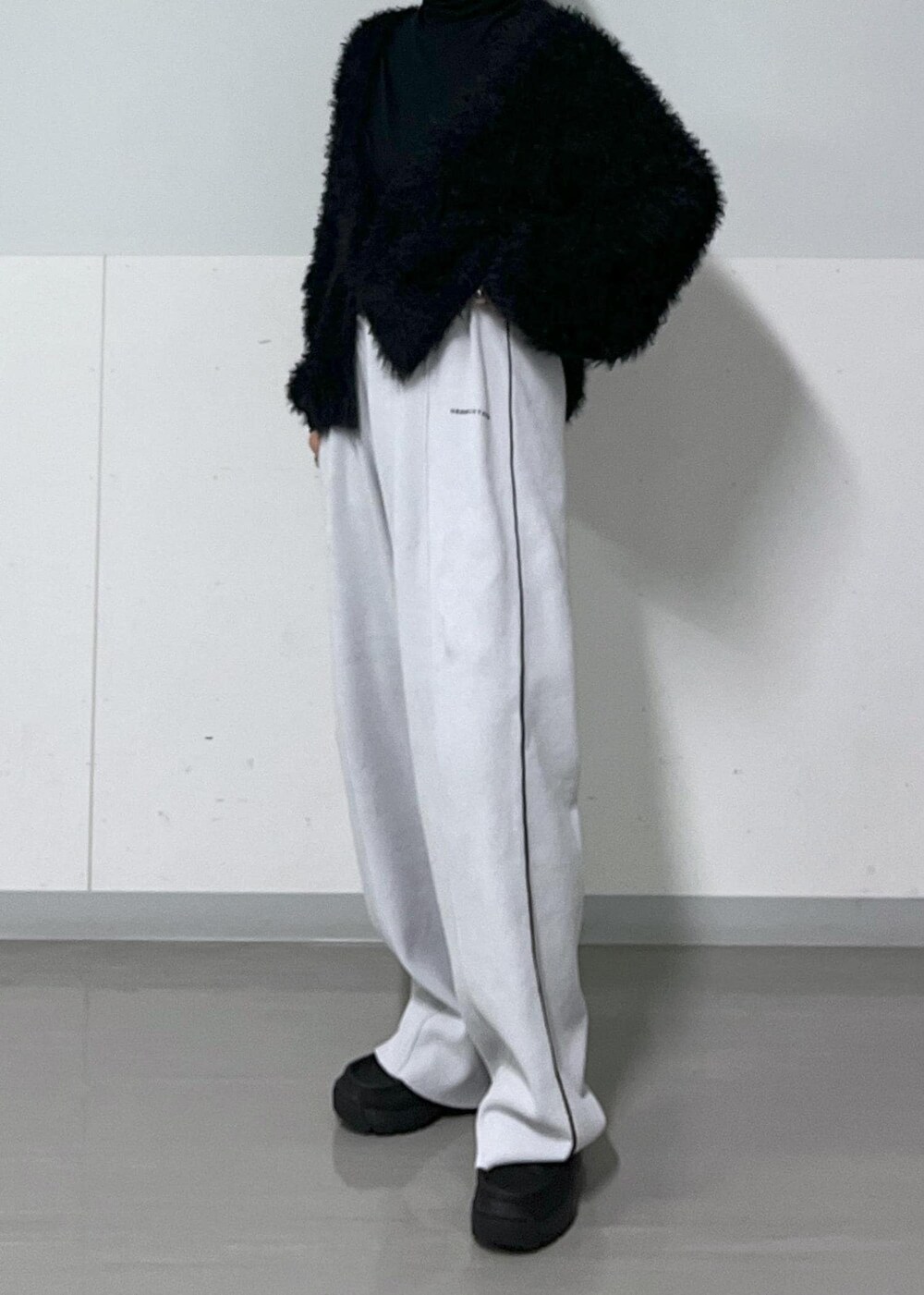 ブラック系のTシャツ/カットソー、ブラック系のモカシン/デッキシューズ、ホワイト系のカーディガン/ボレロを着用したレディースの冬コーディネートの6枚目の写真