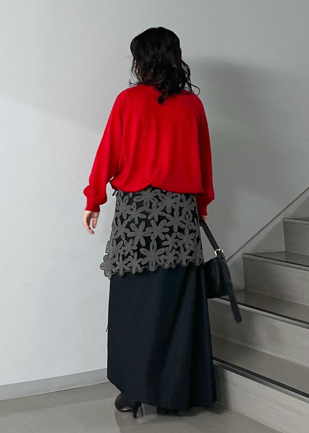 ブラック系のスカート、レッド系のニット/セーター、グレー系のスカートを着用したレディースの秋コーディネートの3枚目の写真