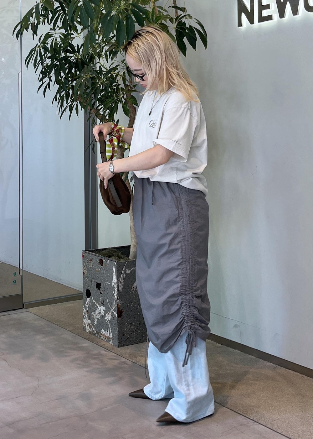 ブルー系のデニムパンツ、グリーン系のパンプス、ブラウン系のショルダーバッグを着用したレディースの夏コーディネートの2枚目の写真