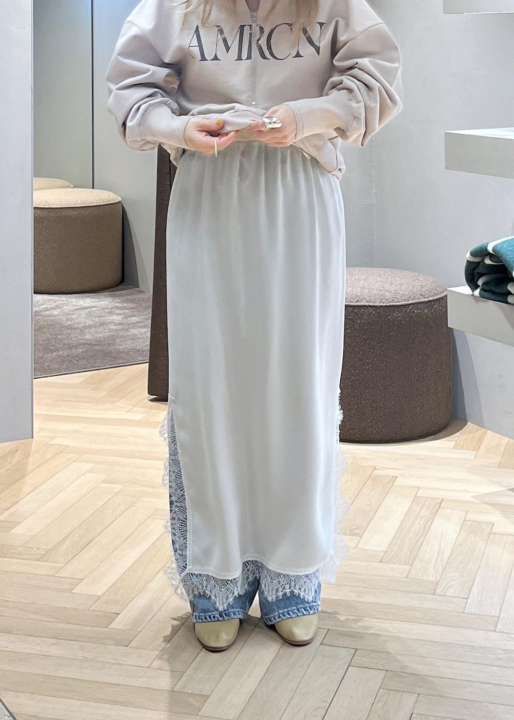 ベージュ系のスウェット、ブルー系のデニムパンツ、ホワイト系のスカートを着用したレディースの冬コーディネートの3枚目の写真