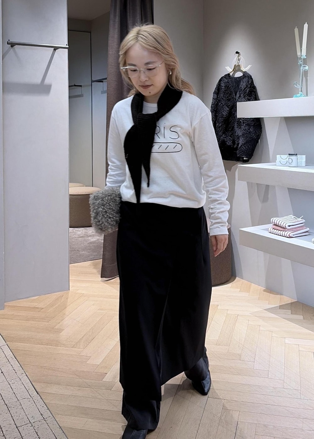 ブラック系のスカート、ホワイト系のTシャツ/カットソー、ベージュ系のショルダーバッグを着用したレディースの秋コーディネートの2枚目の写真