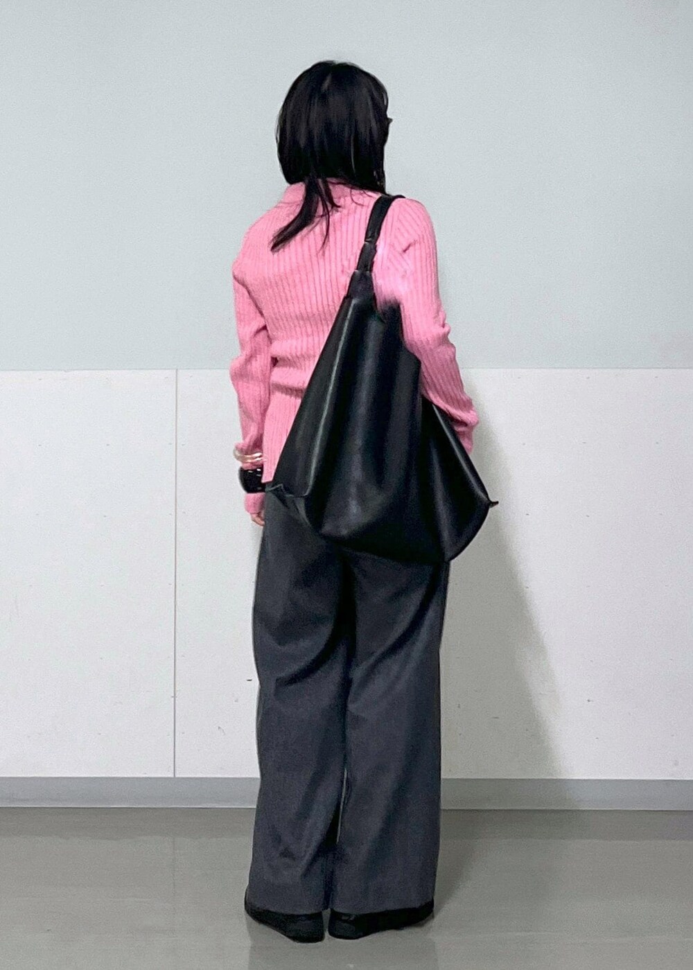 グレー系のスラックス、ブラック系のトートバッグ、ピンク系のニット/セーターを着用したレディースの冬コーディネートの3枚目の写真