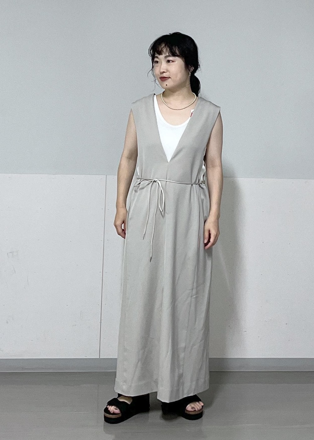 ブラック系のサンダル、ベージュ系のジャンパースカート、ホワイト系のタンクトップを着用したレディースの夏コーディネートの4枚目の写真