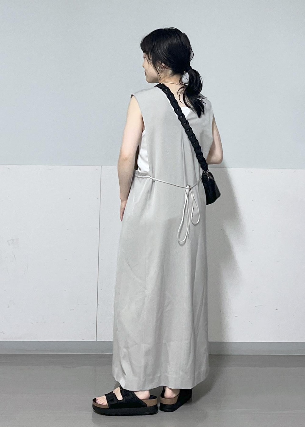 ブラック系のサンダル、ベージュ系のジャンパースカート、ホワイト系のタンクトップを着用したレディースの夏コーディネートの3枚目の写真