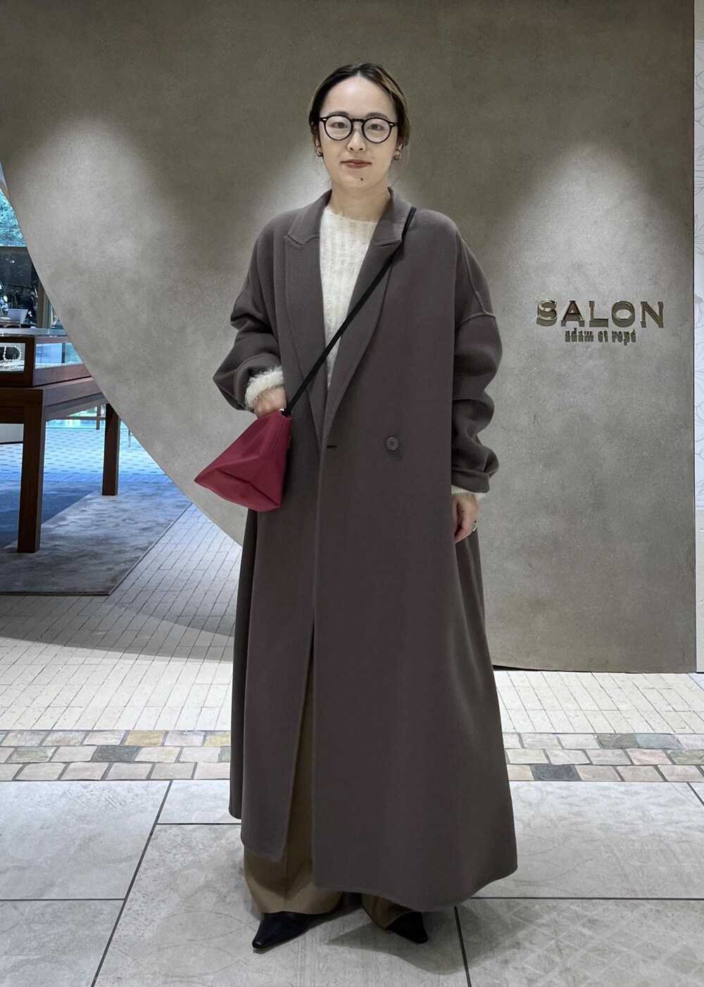 ベージュ系のスラックス、ベージュ系のチェスターコート、ホワイト系のニット/セーターを着用したレディースの秋コーディネートの2枚目の写真