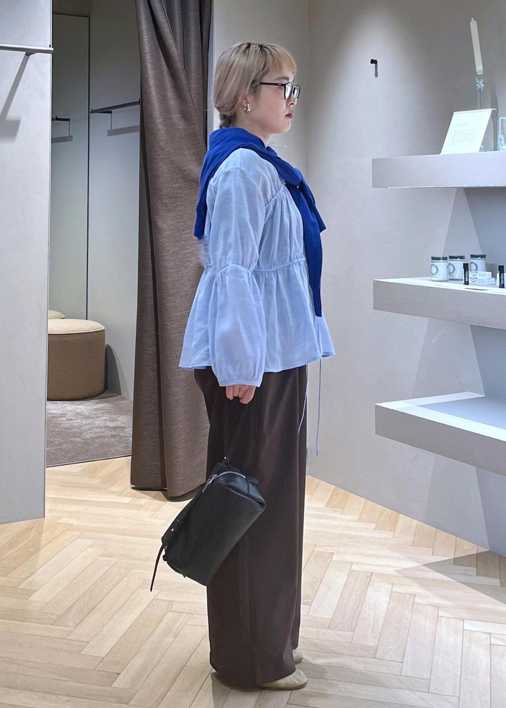 ブラック系のショルダーバッグ、ブラウン系のその他パンツ、ブルー系のニット/セーターを着用したレディースの春コーディネートの2枚目の写真