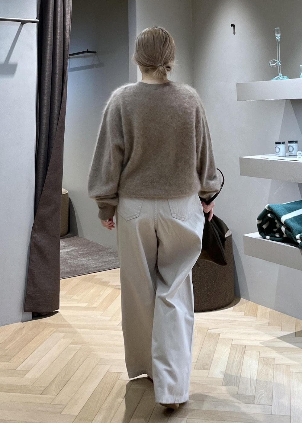 ブラウン系のショルダーバッグ、ベージュ系のニット/セーター、ホワイト系のデニムパンツを着用したレディースの冬コーディネートの3枚目の写真