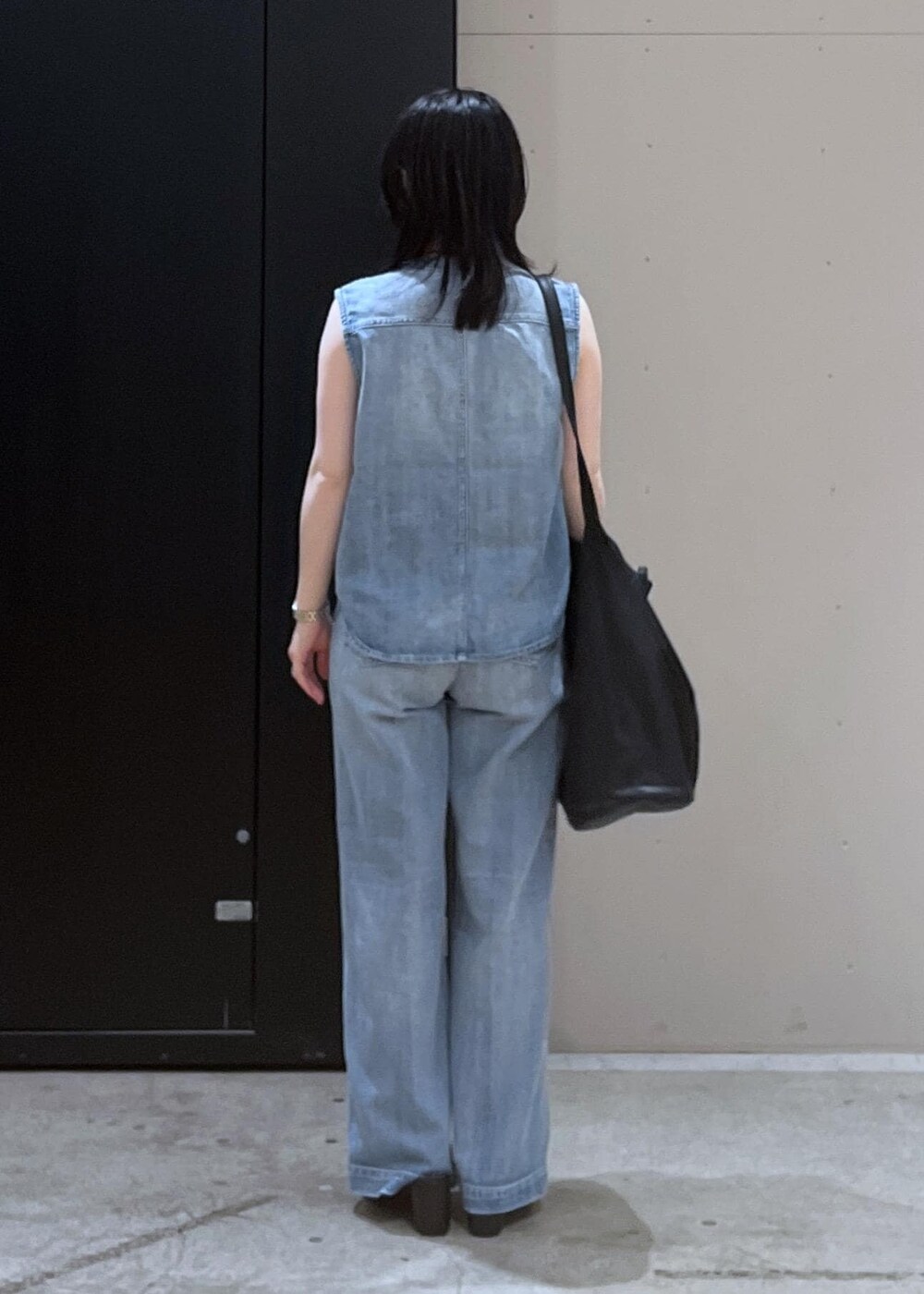 ホワイト系のキャミソール、ブラック系のサンダル、ブルー系のベストを着用したレディースの春コーディネートの3枚目の写真