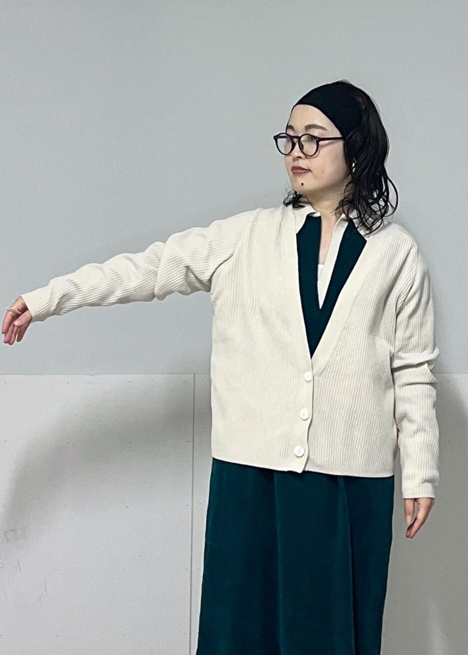 ホワイト系のハンドバッグ、ホワイト系のカーディガン/ボレロ、グリーン系のワンピースを着用したレディースの冬コーディネートの6枚目の写真