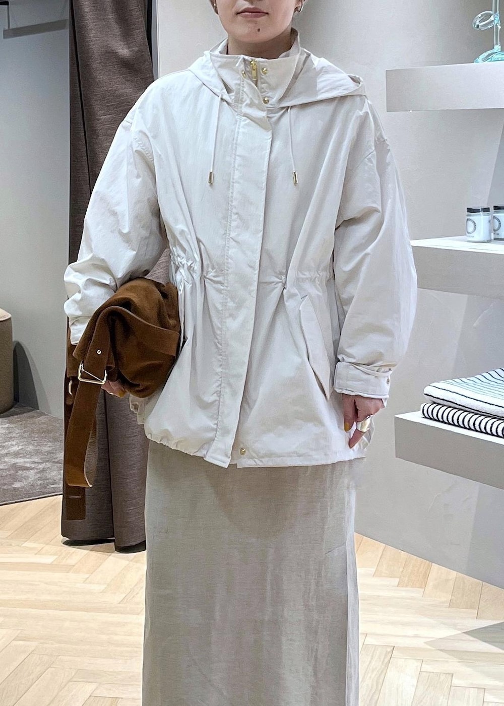 ベージュ系のスカート、ホワイト系のブルゾン、イエロー系のショルダーバッグを着用したレディースの春コーディネートの2枚目の写真