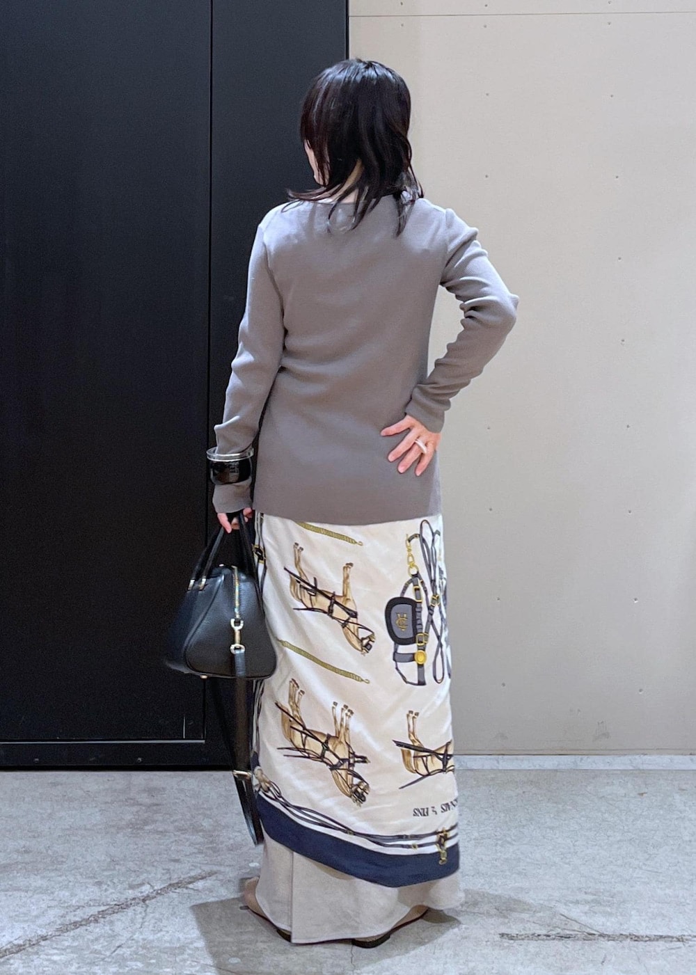 ブラック系のボストンバッグ、ベージュ系のパンプス、ベージュ系のスカートを着用したレディースの冬コーディネートの3枚目の写真