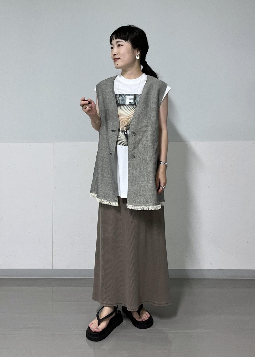 ブラック系のベスト、ホワイト系のTシャツ/カットソー、ブラック系のサンダルを着用したレディースの夏コーディネートの2枚目の写真