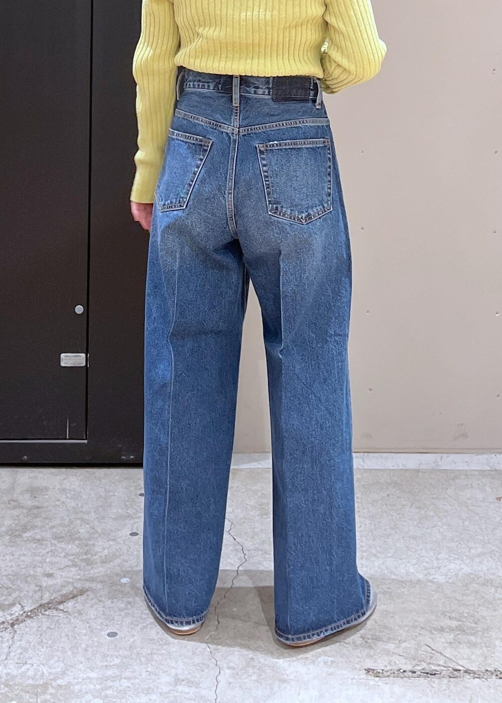 イエロー系のニット/セーター、ブルー系のデニムパンツ、ブラック系のその他アウターを着用したレディースの冬コーディネートの9枚目の写真