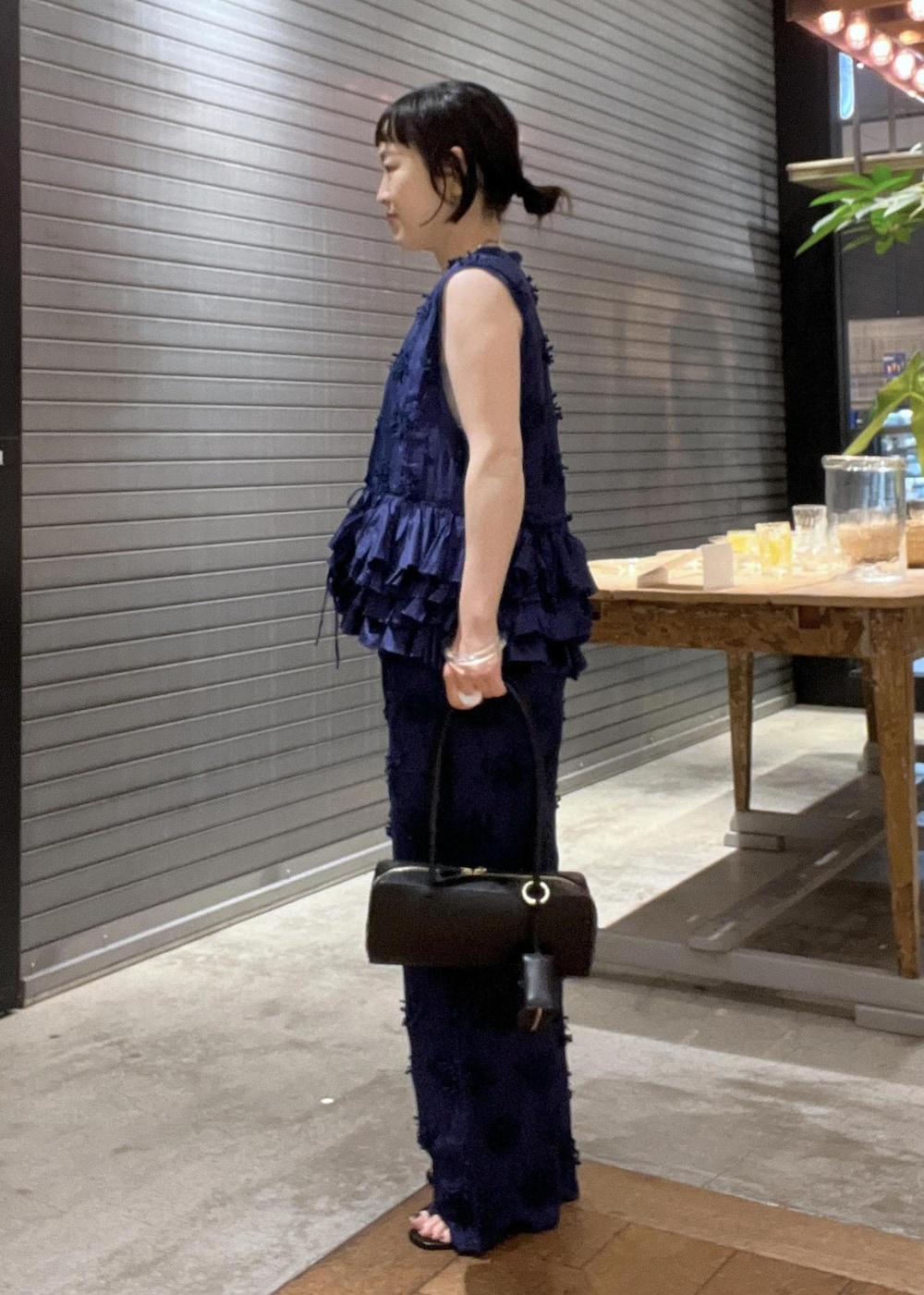 ブラック系のサンダル、ブラック系のショルダーバッグ、グレー系のタンクトップを着用したレディースの夏コーディネートの2枚目の写真