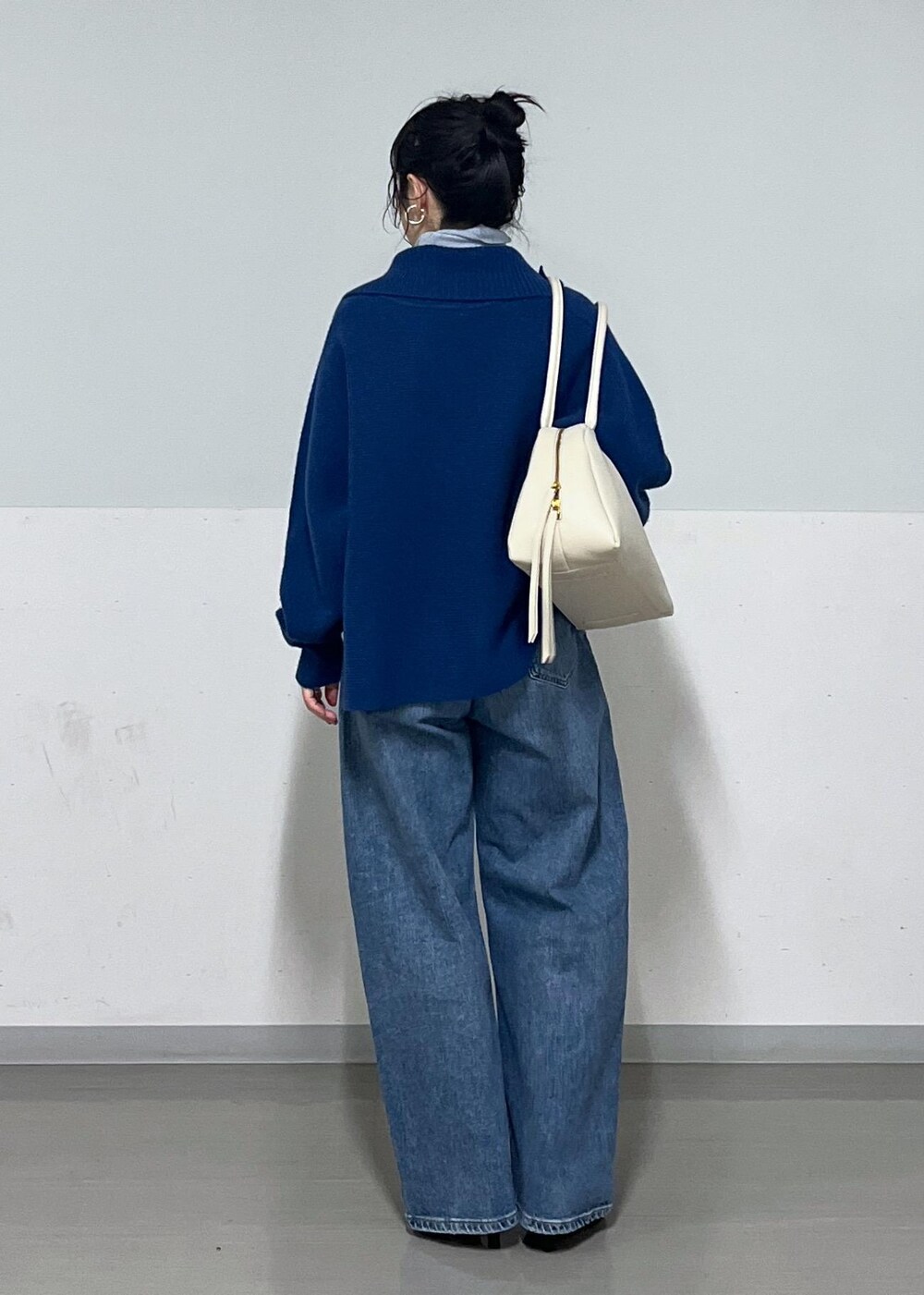 ホワイト系のボストンバッグ、ブルー系のニット/セーター、ブラック系のブーツを着用したレディースの秋コーディネートの3枚目の写真