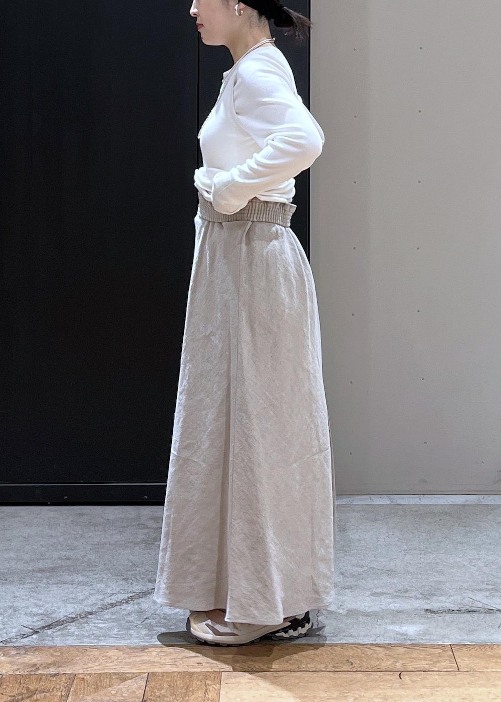 ベージュ系のスニーカー、ベージュ系のスカート、ホワイト系のタンクトップを着用したレディースの春コーディネートの6枚目の写真