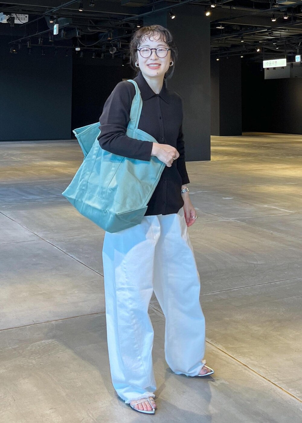 シルバー系のサンダル、ホワイト系のデニムパンツ、ブラック系のハンドバッグを着用したレディースの夏コーディネートの2枚目の写真