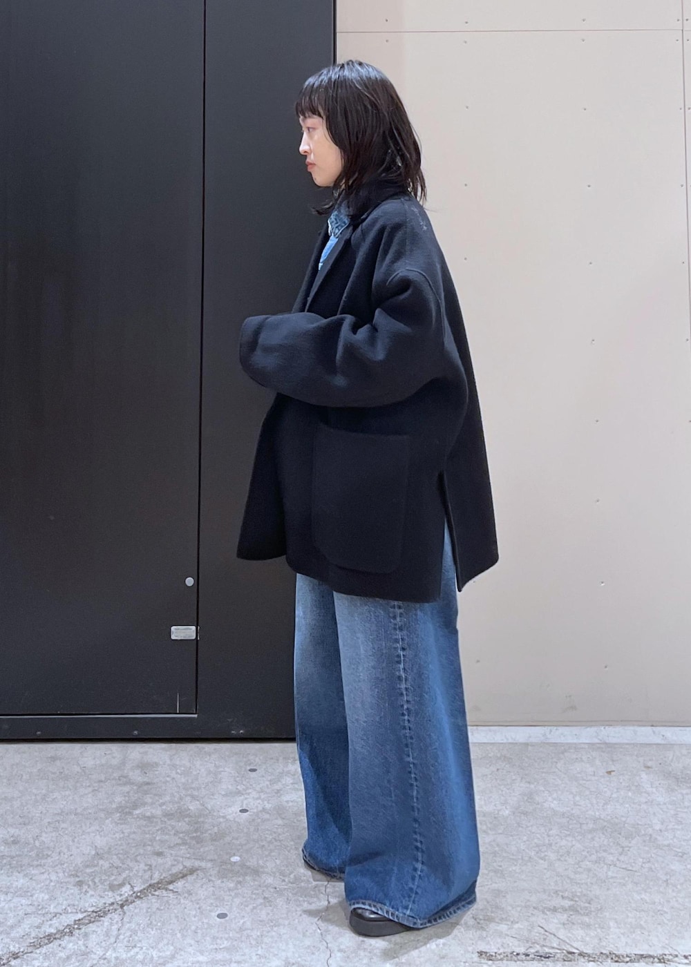 イエロー系のニット/セーター、ブルー系のデニムパンツ、ブラック系のその他アウターを着用したレディースの冬コーディネートの5枚目の写真