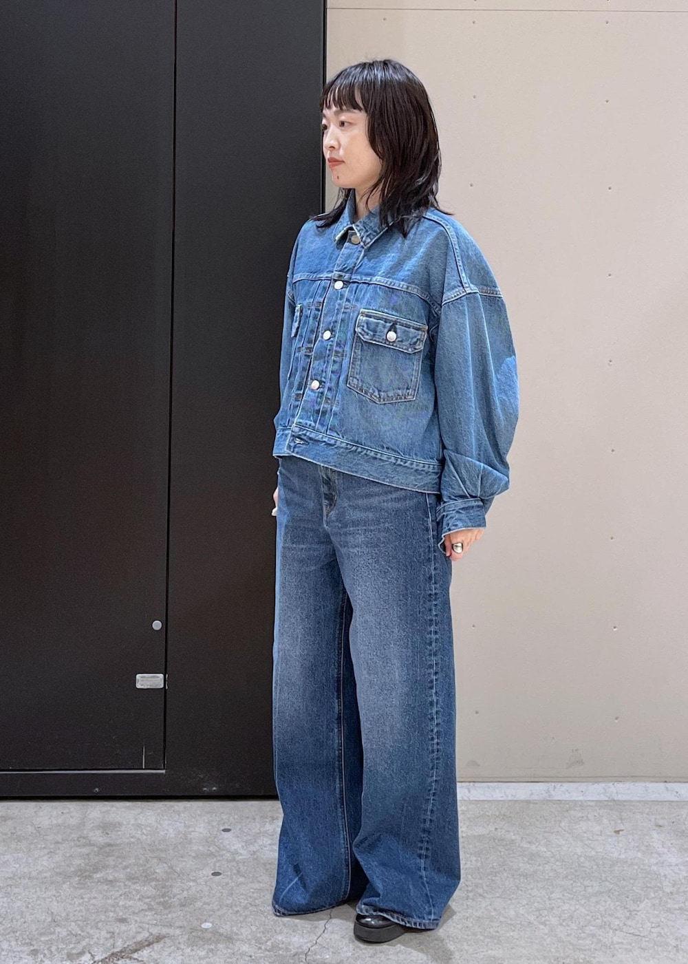 イエロー系のニット/セーター、ブルー系のデニムパンツ、ブラック系のその他アウターを着用したレディースの冬コーディネートの6枚目の写真