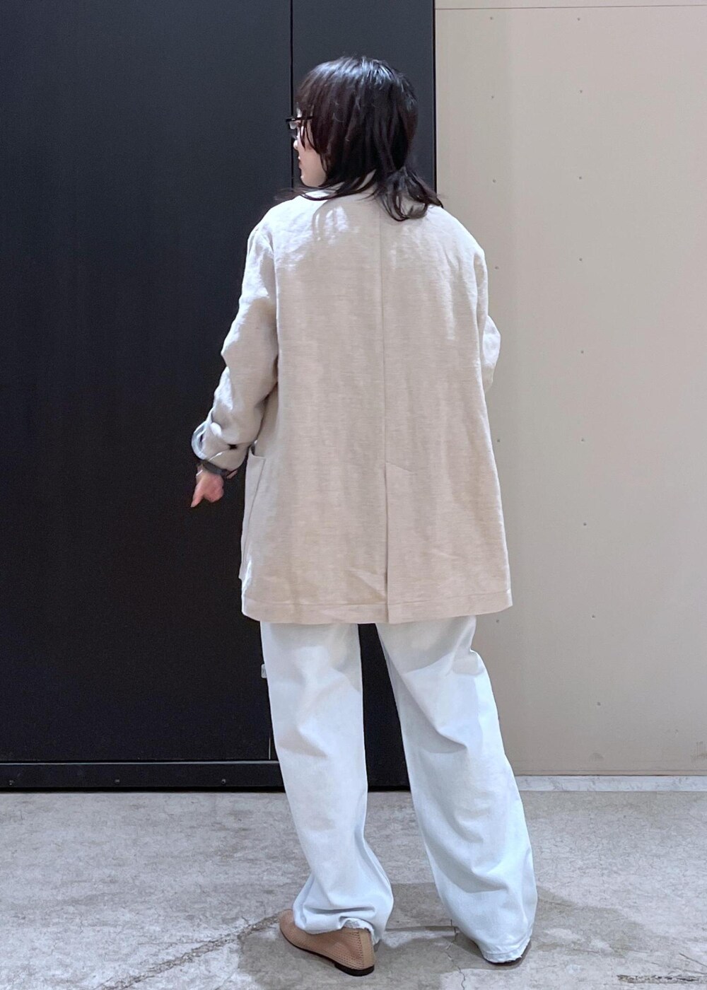 ベージュ系のボストンバッグ、ベージュ系のパンプス、ブルー系のデニムパンツを着用したレディースの冬コーディネートの3枚目の写真