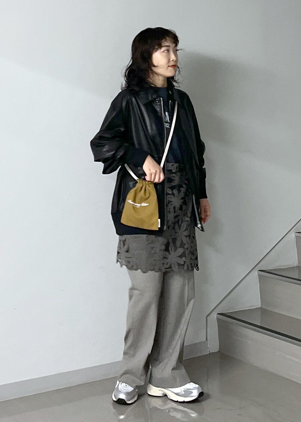 ブルー系のトートバッグ、グレー系のスラックス、ブラック系のTシャツ/カットソーを着用したレディースの秋コーディネートの2枚目の写真