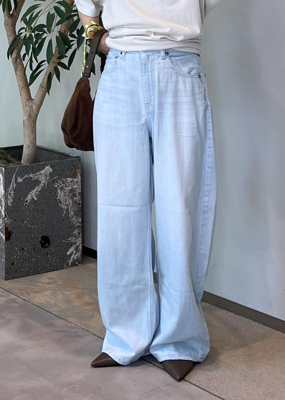 ブルー系のデニムパンツ、グリーン系のパンプス、ブラウン系のショルダーバッグを着用したレディースの夏コーディネートの6枚目の写真