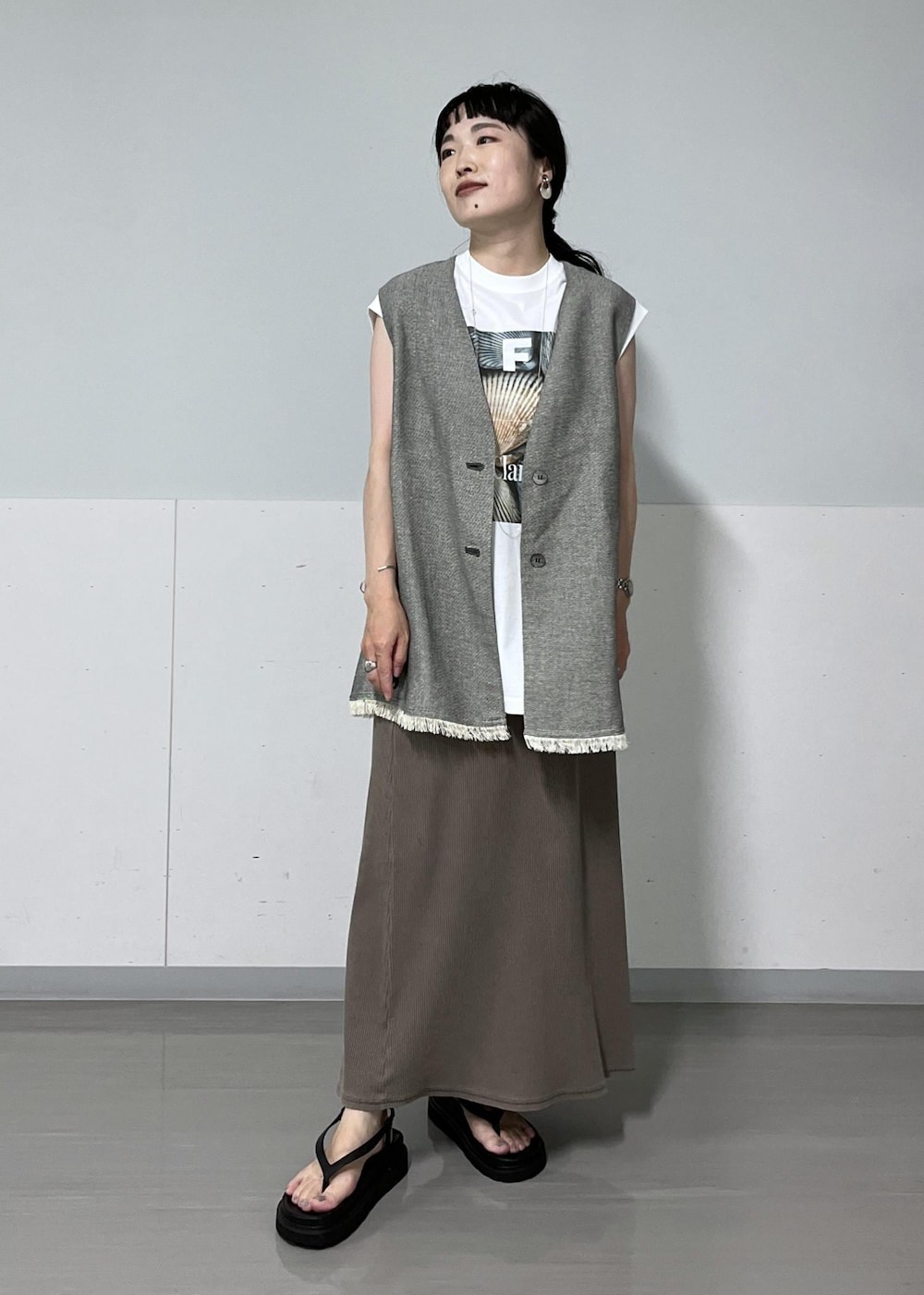 ブラック系のベスト、ホワイト系のTシャツ/カットソー、ブラック系のサンダルを着用したレディースの夏コーディネートの3枚目の写真