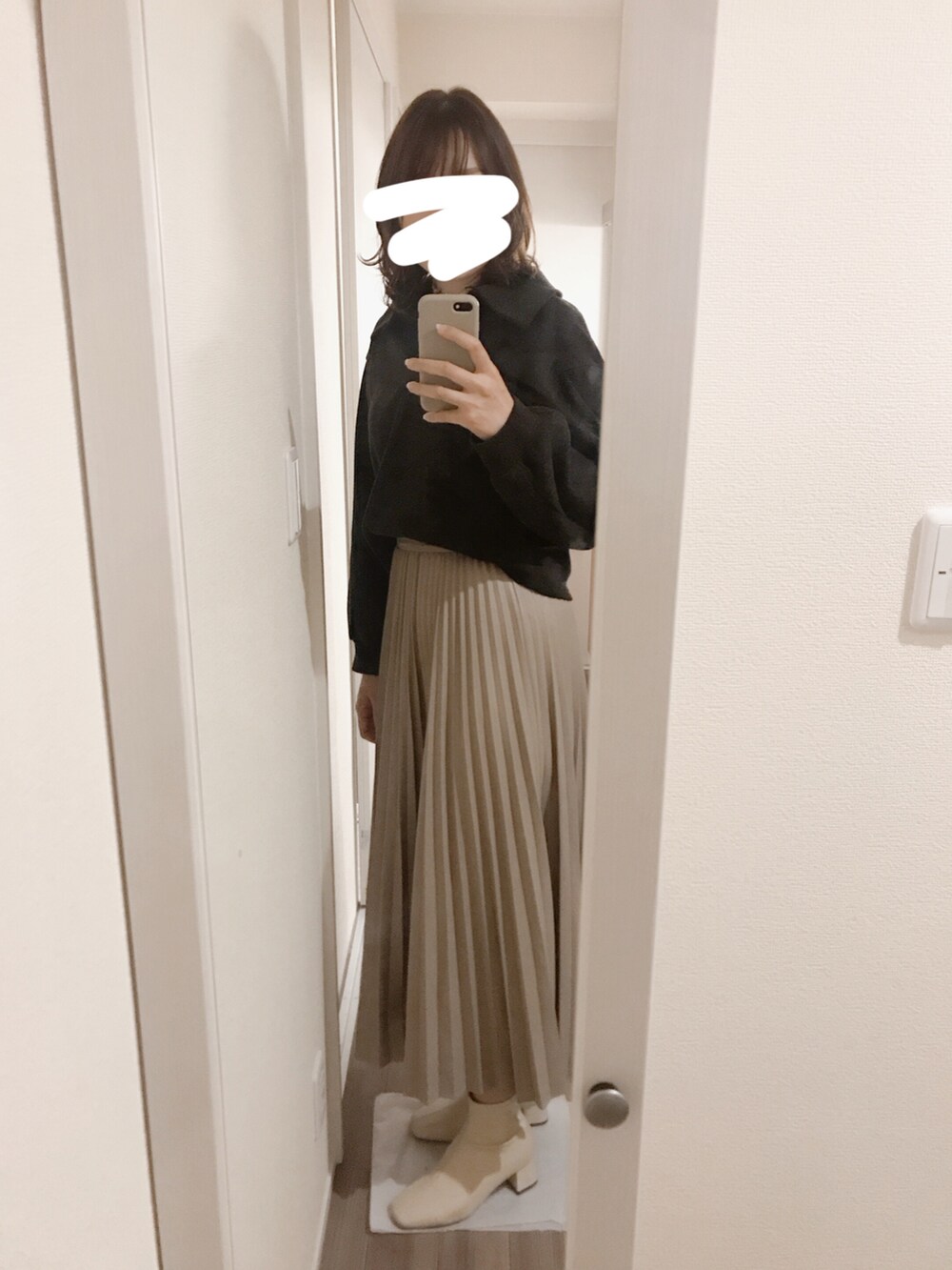 ブラック系のトップス、ベージュ系のスカート、ホワイト系のブーツを着用したレディースの冬コーディネートの2枚目の写真