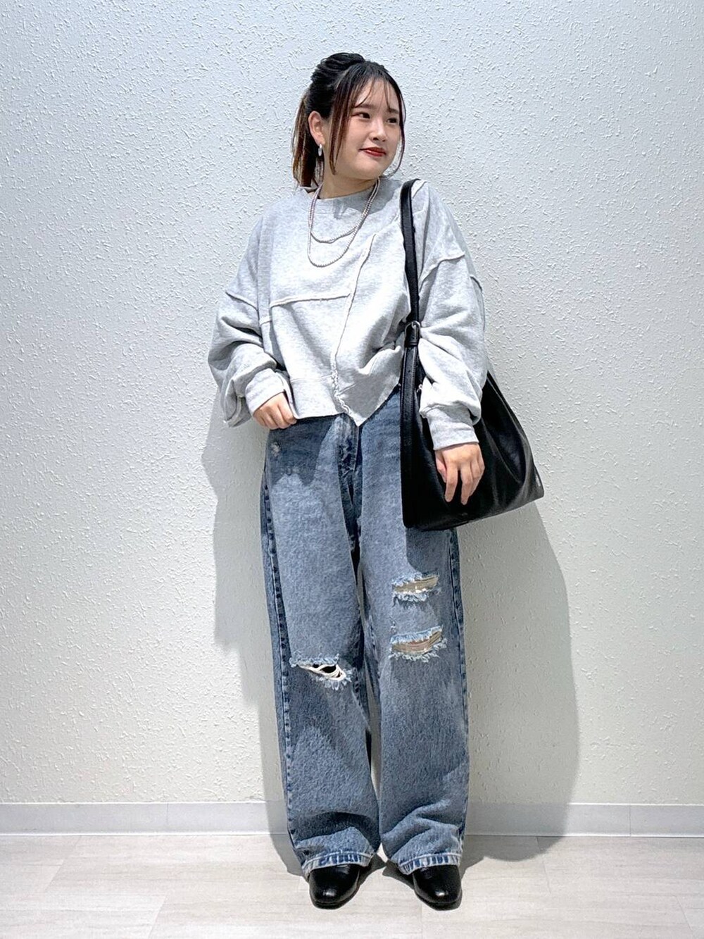 ブルー系のデニムパンツ、ブラック系のブーツ、グレー系のスウェットを着用したレディースの秋コーディネートの2枚目の写真